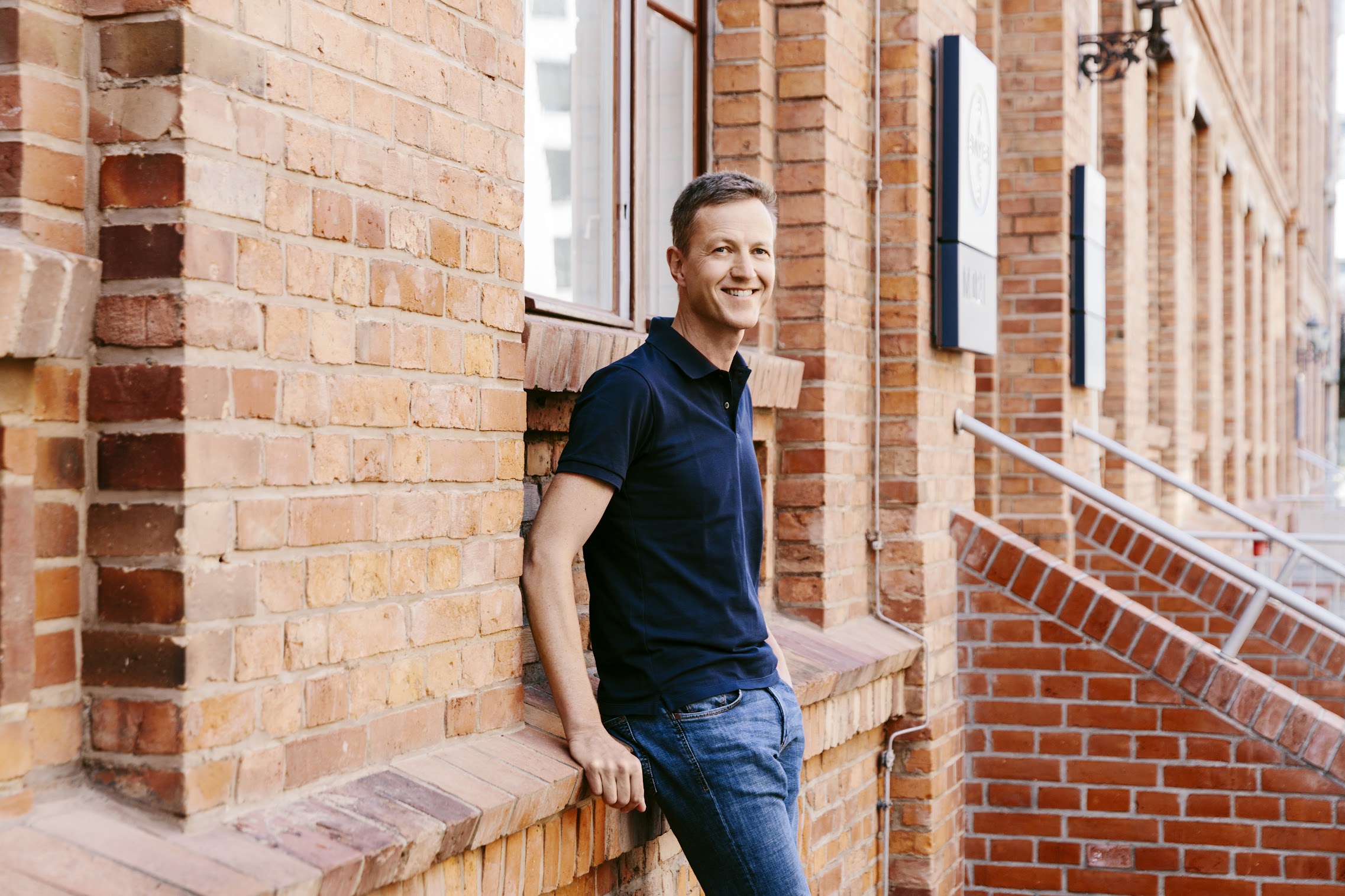 Juergen leaning against a red brick wall